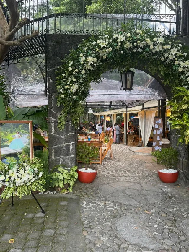 Mesa larga al aire libre con flores de colores colgando para una comida familiar