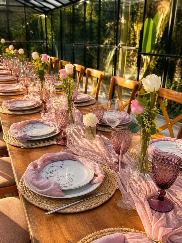 Mesa en tonos rosas con copas labradas y rosas a la luz dorada de la tarde en la Capilla de Cristal