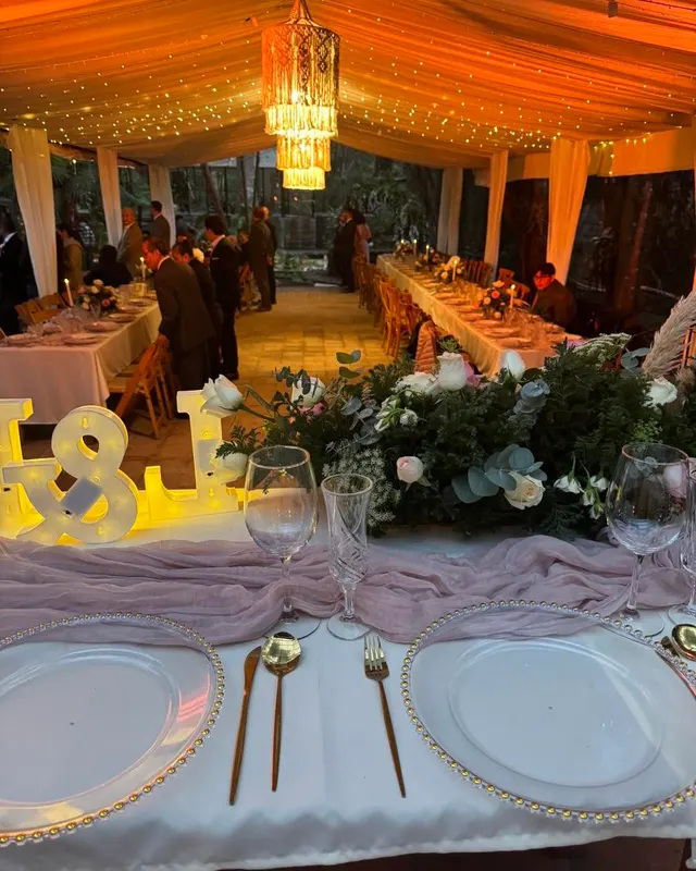 Letras luminosas con las iniciales de los novios al anochecer bajo el pabellón