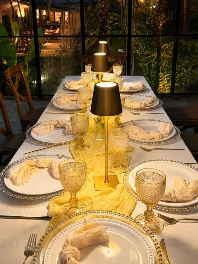 Mesa nocturna con lámparas doradas y vista al jardín iluminado