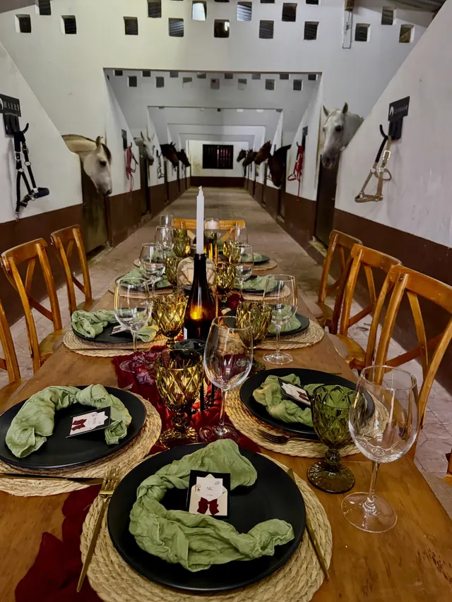 Cena servida en las caballerizas, con los caballos asomados a la mesa