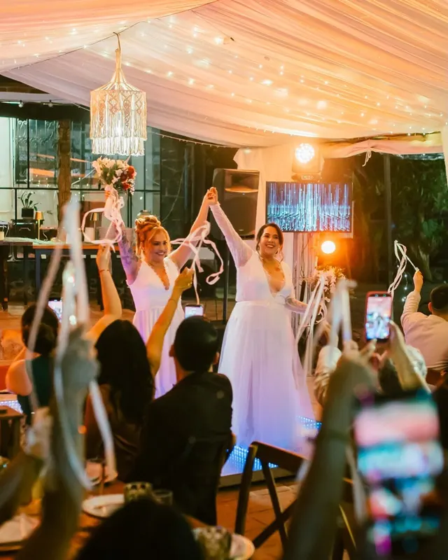 Novias celebrando de noche entre listones y luces del pabellón