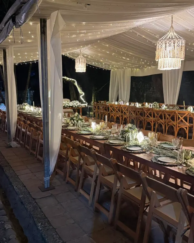 Mesa larga de madera con candiles de macramé encendidos al final de la noche